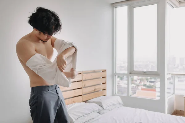 Man is taking off his t-shirt in his bedroom apartment. — Stock Photo, Image