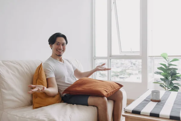 Happy man sits and relax on the sofa in the living room of the apartment.