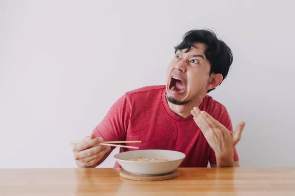 Faccia divertente dell'uomo mangiare molto caldo e piccante tagliatella istantanea. — Foto Stock