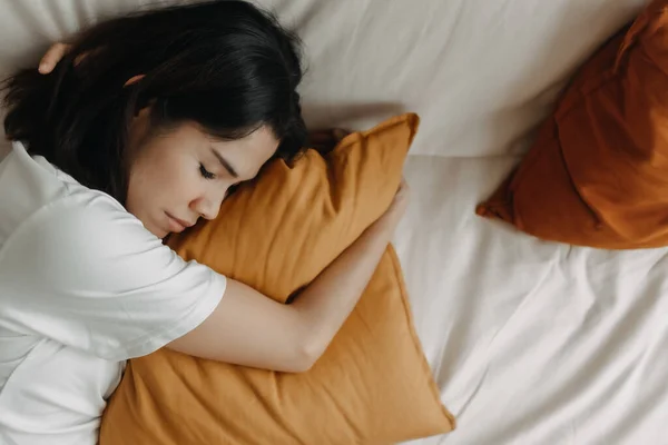 Kobieta drzemie lub śpi na kanapie z żółtą poduszką. — Zdjęcie stockowe