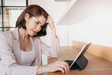 Mutlu çalışan kadın ofiste bir tablet kullanıyor..