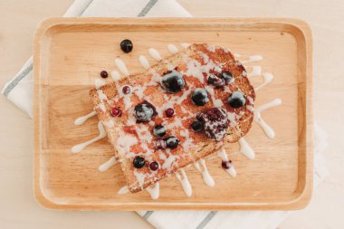 Böğürtlenli tost ekmeği ve ahşap tabakta konsantre süt..