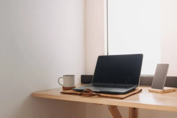 Espacio de trabajo para ordenador portátil en un escritorio de madera junto a las ventanas. — Foto de Stock