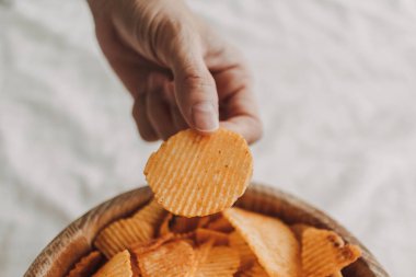 Beyaz yatakta bir kase patates cipsi..