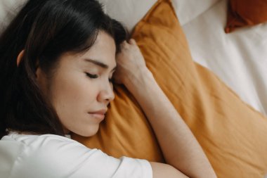 Kadın ya kestiriyor ya da sarı yastıkla kanepede uyuyor..