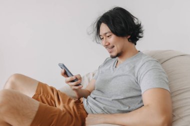 Adam akıllı telefon kullanırken koltukta oturup rahatlıyor..