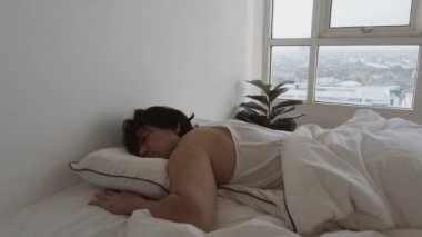 Bir adam uyanıyor beyaz yatağında, yatak odasının dairesinde, rahat, tembel bir sabah.