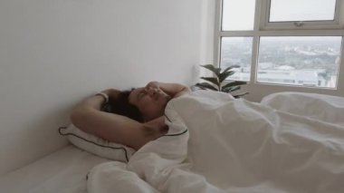 Bir adam uyanıyor beyaz yatağında, yatak odasının dairesinde, rahat, tembel bir sabah.