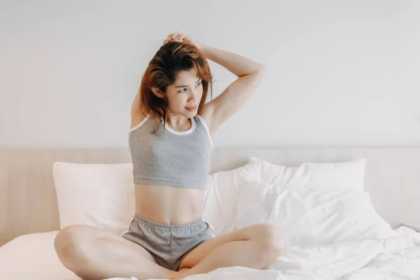Aantrekkelijke vrouw in ondergoed stretching op het bed in de ochtend. — Stockfoto
