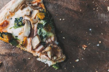 Yuvarlak ahşap tabakta servis edilen mantarlı ve kabaklı ev yapımı pizza..