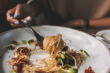 Kadın pastırmalı ve ayçiçekli spagetti yiyor..