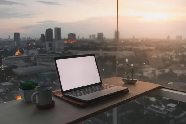 Laptop på skrivbordet vid balkongen med kvällsutsikt över solnedgången. — Stockfoto