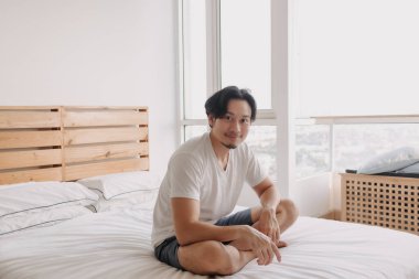 Mutlu adam evinde yatağında oturur ve dinlenir..