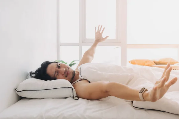 El hombre acaba de despertar en una mañana feliz en el dormitorio blanco brillante. — Foto de Stock