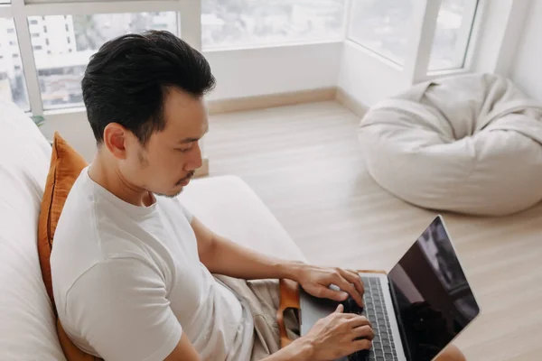 Man berkonsentrasi pada pekerjaannya pada laptop di apartemennya. — Stok Foto