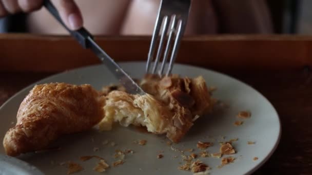 Frau isst Croissants mit Gabel und Messer im Café. — Stockvideo