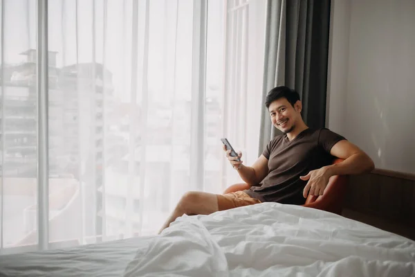 El hombre se siente feliz con el resultado de su teléfono mientras está de vacaciones en el hotel. —  Fotos de Stock