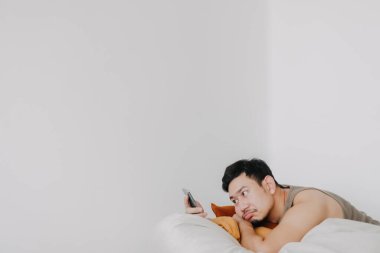 Sıkılmış ve üzgün bir adam cep telefonu kullanıyor ve puf puf koltukta dinleniyor..