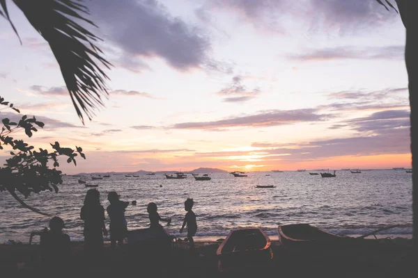 Silhouette der Kinder der Fischerstadt spielen am Strand bei Sonnenuntergang. — Stockfoto