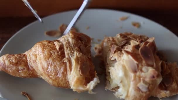 A nő villával és késsel eszik croissant-t a kávézóban.. — Stock videók