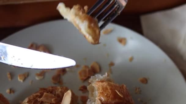 Femeia mănâncă croissante cu furculiță și cuțit în cafenea. — Videoclip de stoc