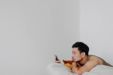 Sıkılmış ve üzgün bir adam cep telefonu kullanıyor ve puf puf koltukta dinleniyor..