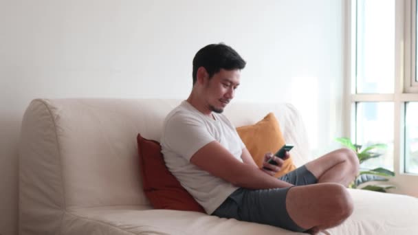 Happy man use his mobile phone in the living room in a casual day. — Stock Video