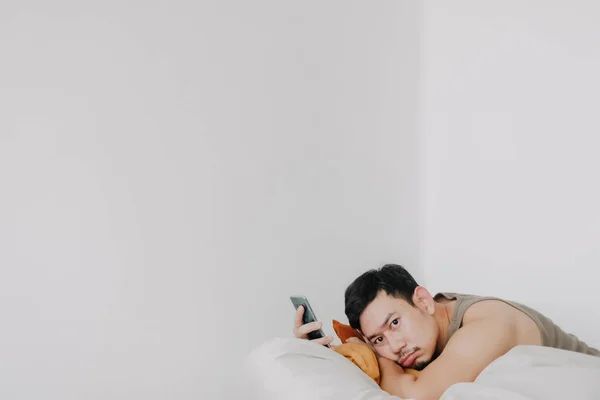 Homem entediado e triste usando telefone celular e relaxado no sofá beanbag. — Fotografia de Stock