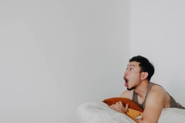 Şaşırmış ve şaşırmış bir Asyalı adam, fasulye torbasında yatarken boşluğu işaret ediyor..