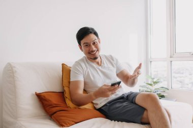 Happy asian man use smartphone in the living room for advertising content.