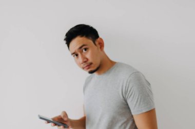 Beyaz arka planda mobil uygulama kullanan Asyalı adamın endişeli yüzü.