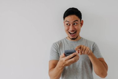 Vay ve sürpriz yüz Asyalı adam akıllı telefon ve reklam alanı kullanıyor..