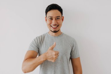 Mutlu Asyalı adam beyaz arka planda iyi bir el işareti olarak baş parmağını gösteriyor..