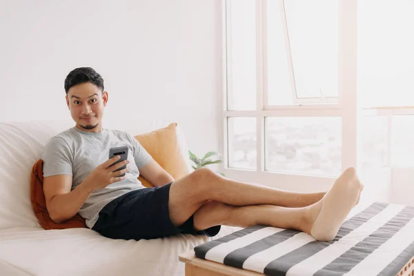 Asian man feels relax and relief with trading business on mobile in his home.