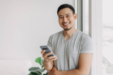 Young happy smiling asian man using smartphone feel relax and comfortable.