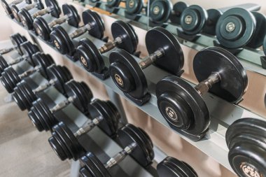 Spor salonundaki metal raflarda siyah halterler..