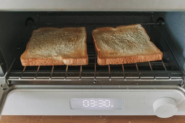 Automatic white breads toaster steamed oven with breads inside in the kitchen.