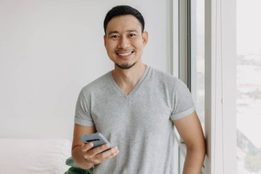 Young happy smiling asian man using smartphone feel relax and comfortable.