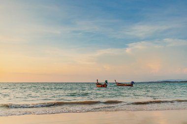 Phuket Thailand 'daki Mai Khao Sahili' nin gün batımı manzarası ve iki uzun kuyruk teknesi..