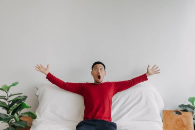 Surprised face asian man in the house with advertising copy space on the wall.