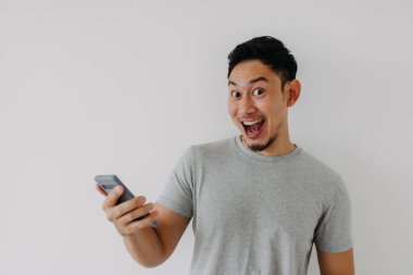 Vay ve sürpriz yüz Asyalı adam akıllı telefon ve reklam alanı kullanıyor..