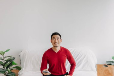 Happy asian man on sofa use phone for trading business with advertising space. 
