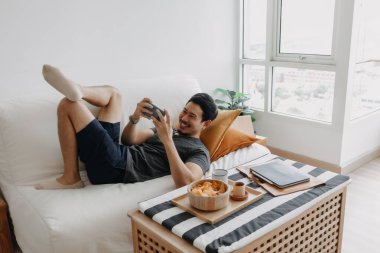 Evde çalışması gerekirken gezici oyun oynayan tembel mutlu Asyalı adam..