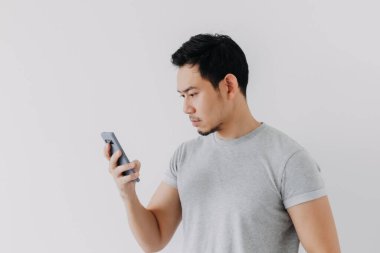 Asian man seriously concentrated on smartphone isolated on white background.