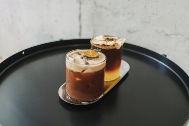 Kafedeki siyah masada servis edilen iki buzlu portakallı kahve..