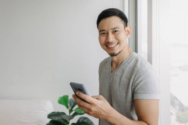 Young happy smiling asian man using smartphone feel relax and comfortable.