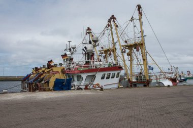 Güneşli bir pazar günü Lauwersoog limanında ağlı balıkçı tekneleri uzanıyor.