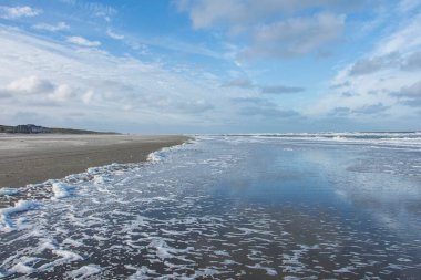 Wadden Adası 'nın kum tepeleriyle Nortsea' nin kumlu sahilinde dalgalar.