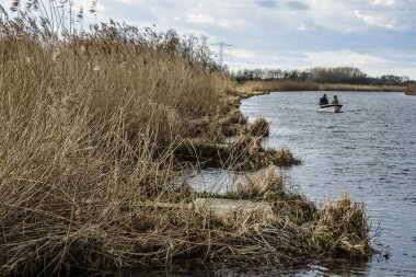 Sonbaharda Oude IJssel nehrinde balıkçı teknesinde balık tutan iki balıkçı.