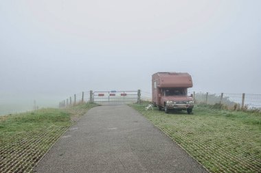 Sonbaharda sisli bir günde Oude IJssel nehrinin yakınındaki bir park yerinde kamp arabası.